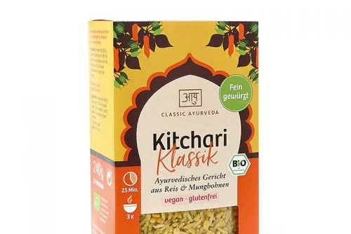 Gelbe und orange box mit ayurveda kitchari rezept classic und dekorativem bogen mit blättern und chilischoten