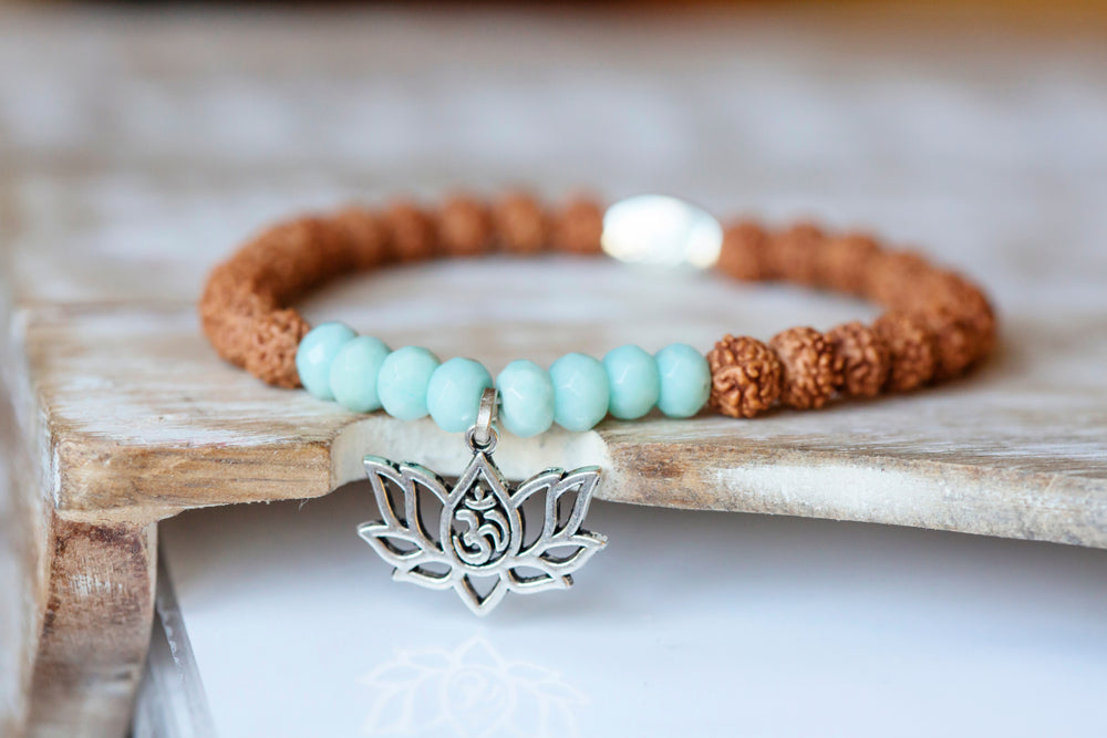 Eine zarte silberne lotus anhänger an einem perlenarmband mit hellblauen und braunen perlen im mana shop bern
