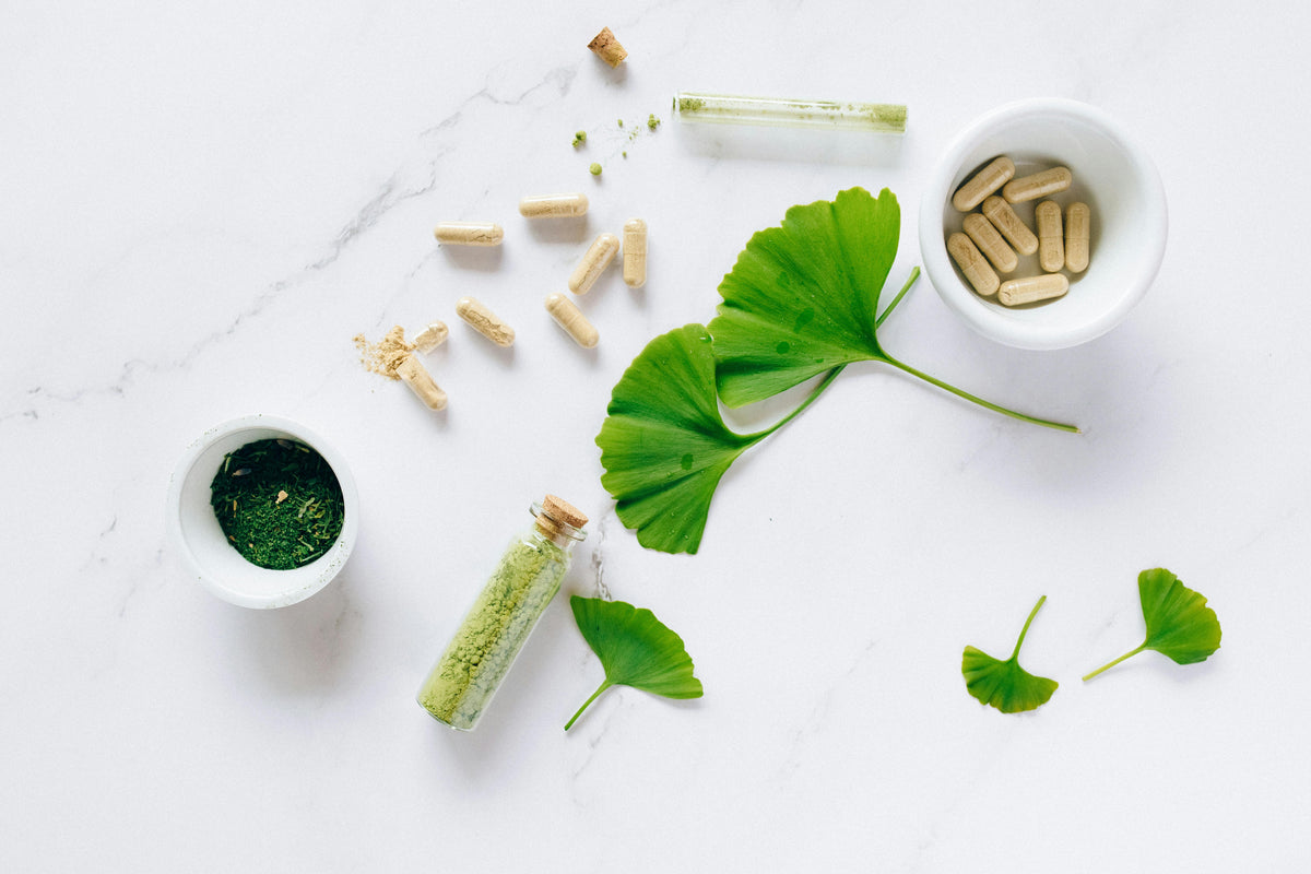 Ein kleines klares glasfläschchen mit korkverschluss gefüllt mit grünem pulver als ayurveda immun-booster tipps