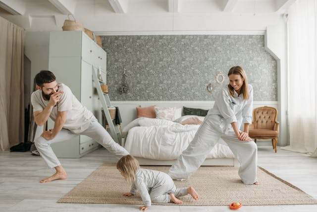Eine familie in passenden hellgrauen loungewear posiert auf beigem teppich für ayurvedische morgenrituale und innere ruhe