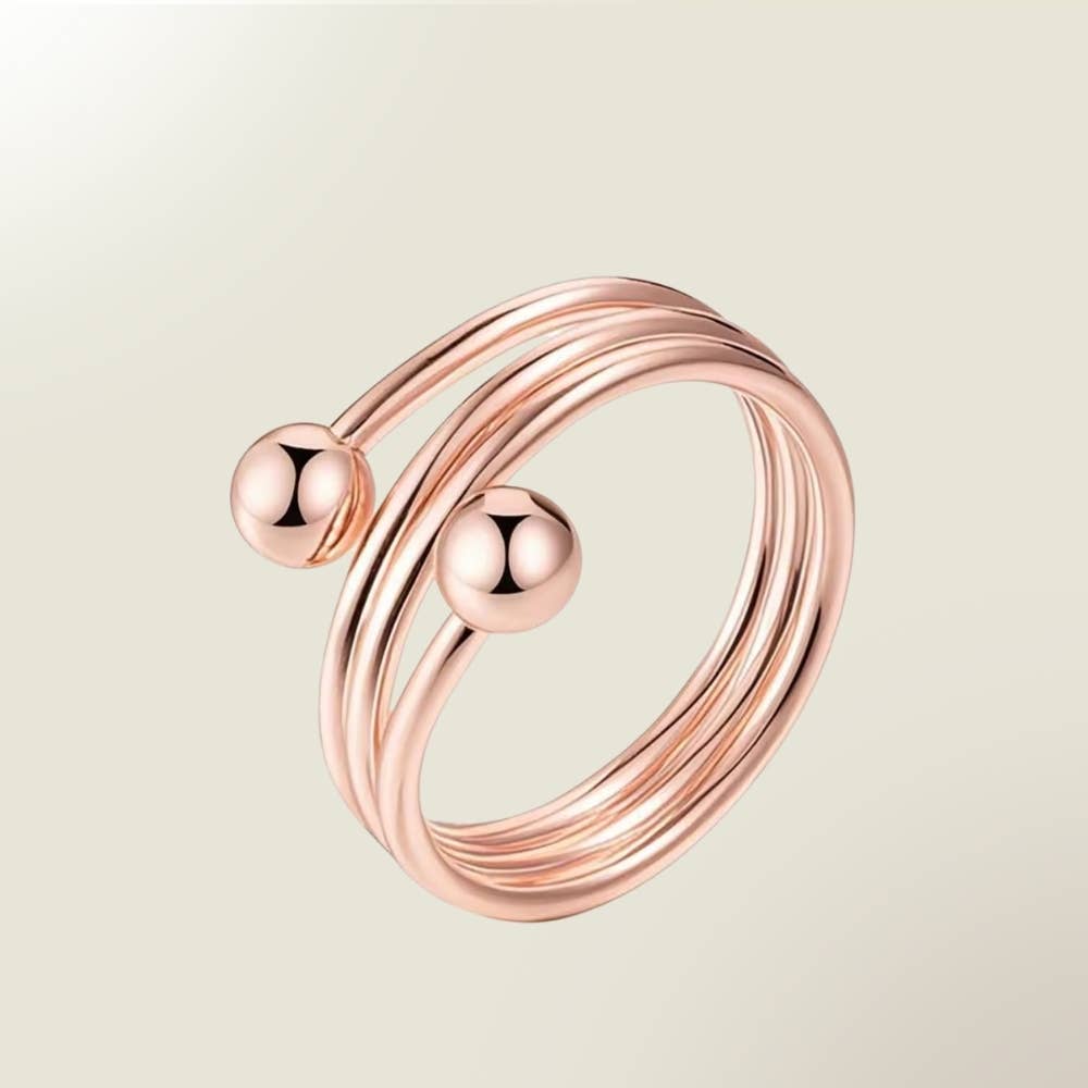 Ein tibetisches kupferarmband mit drei ineinander verschlungenen rosegoldbändern und zwei polierten kugeln