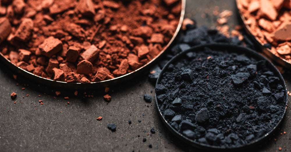 Natürliche Bio-Kosmetik-Pigmente in braun und dunkelblau auf dunklem Untergrund