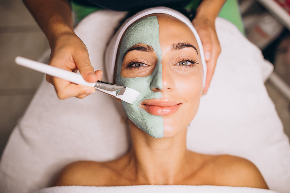 Frau erhält eine pflegende Gesichtsmaske mit einem Pinsel im Spa.