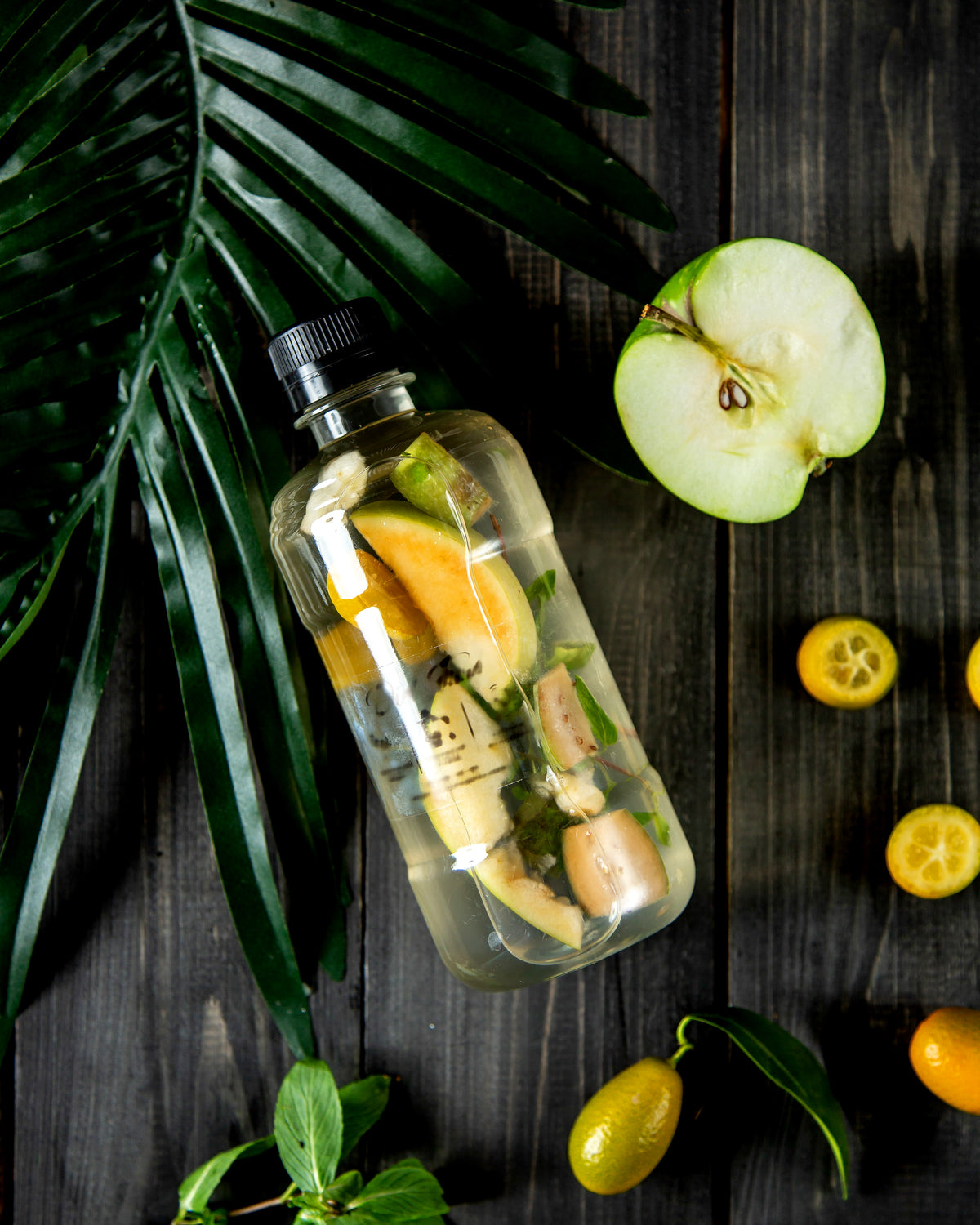 Infused Wasser mit frischem Obst und Äpfeln auf dunklem Holzhintergrund