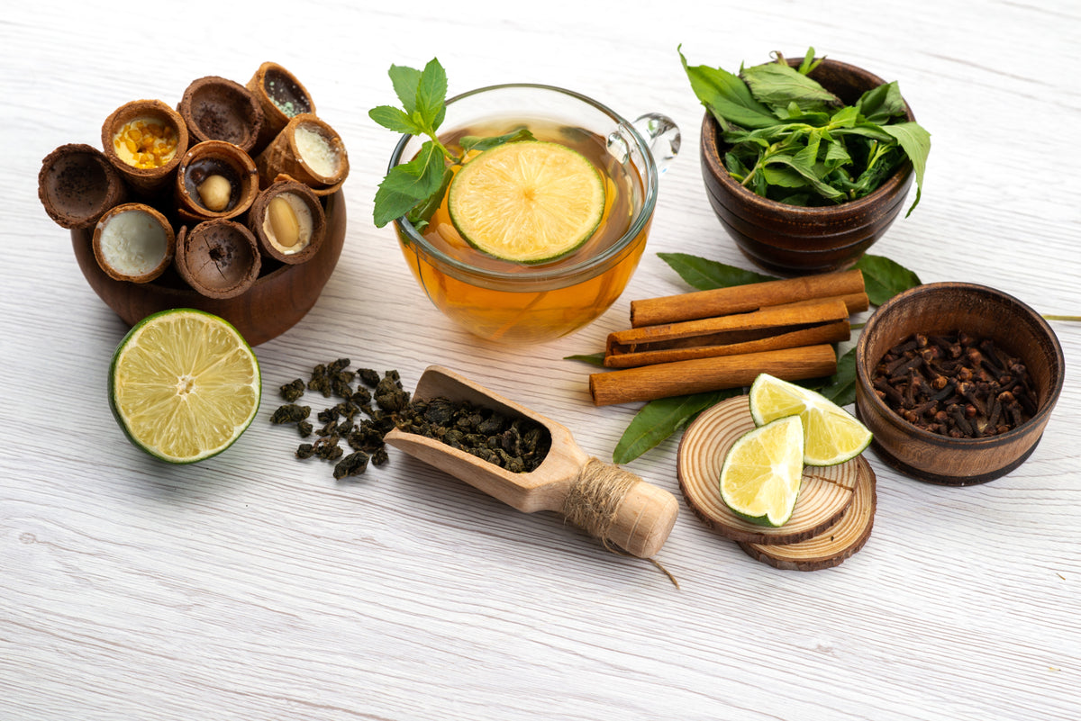 Frischer Bio-Minztee mit Limette, Zimtstangen, Gewürzen und gesunden Schokoladen-Snacks.