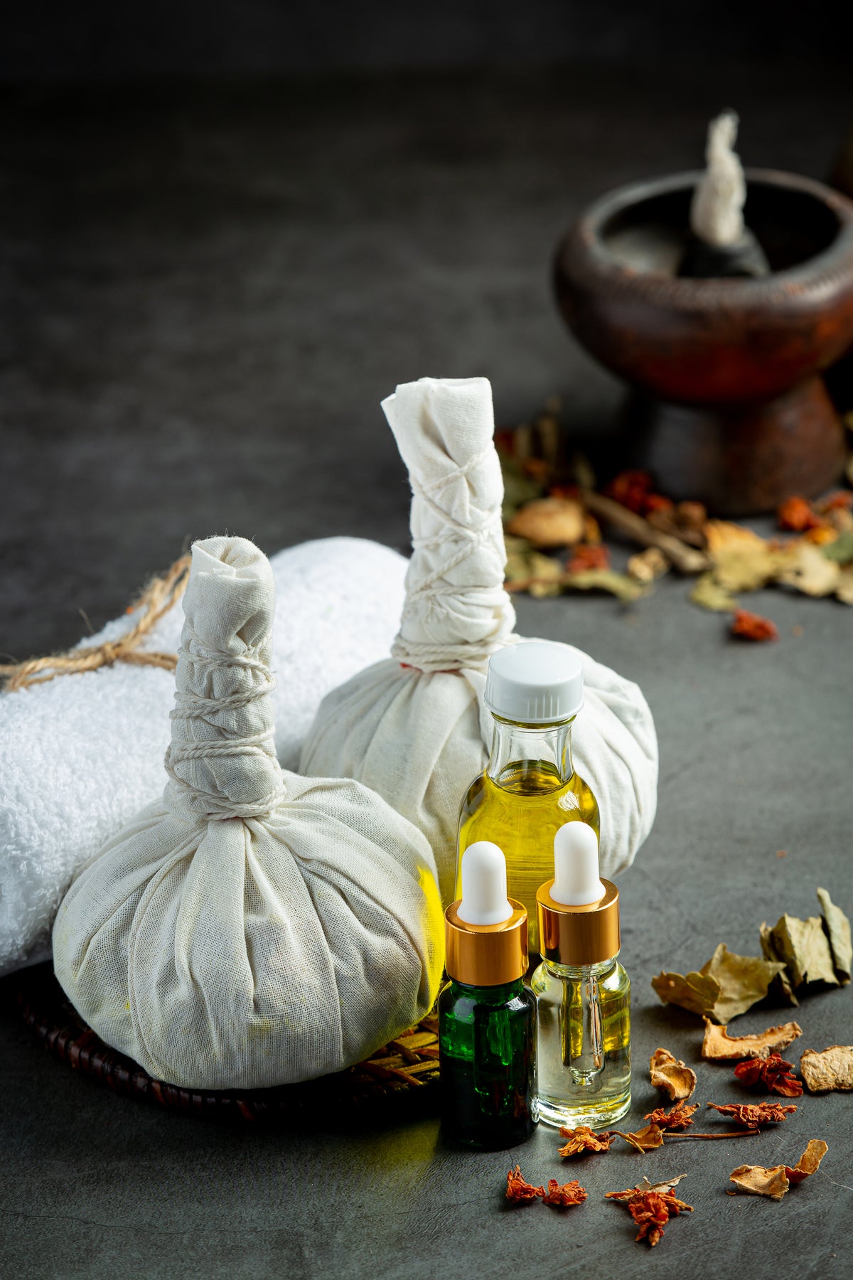 Traditionelle Kräuterkompressen und ätherische Öle für die Wellness-Anwendung.