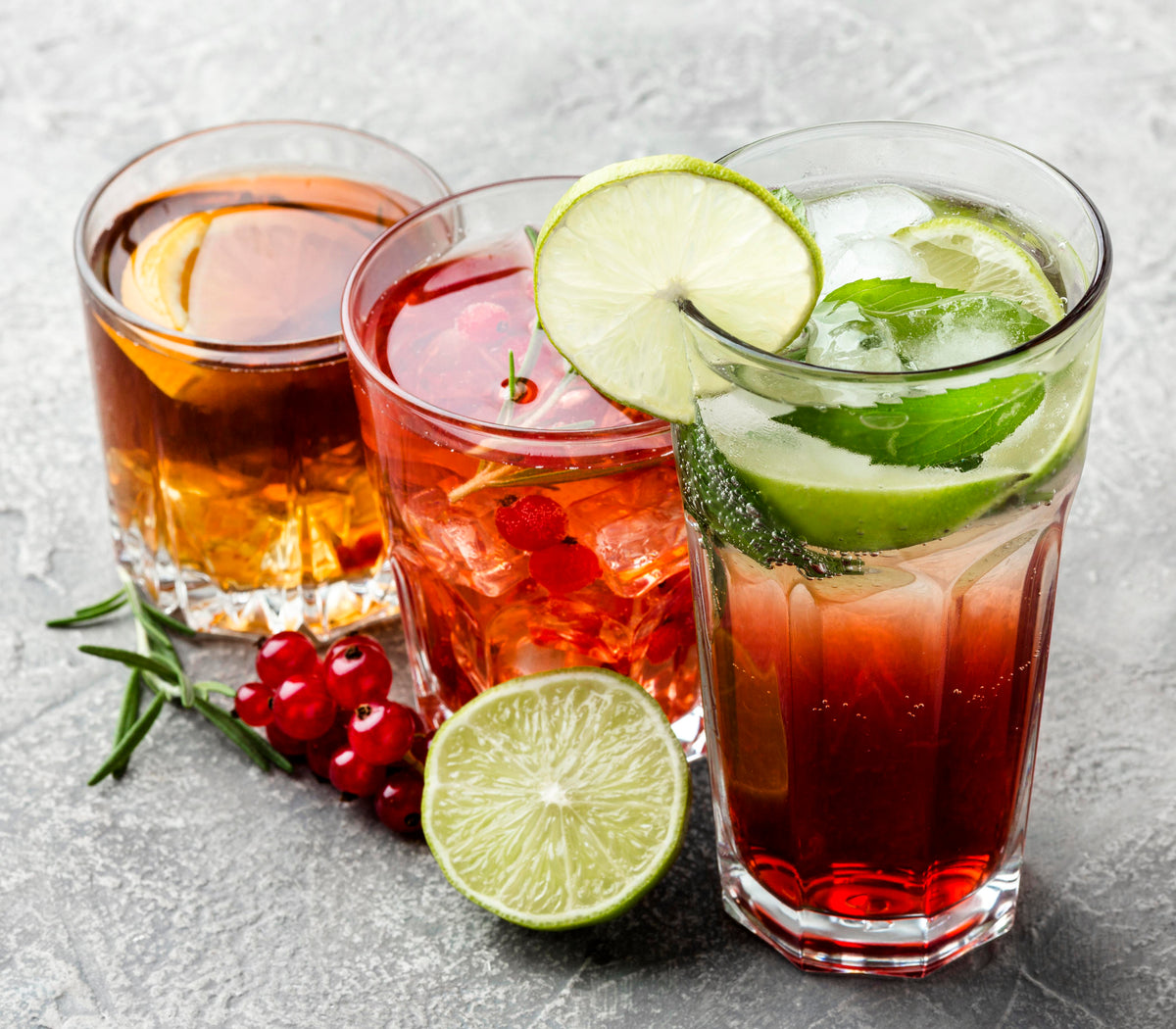 Erfrischende Sommercocktails mit Limette, Minze und roten Beeren in Gläsern.
