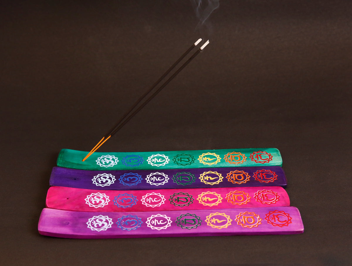Bunte Räucherstäbchen-Halter aus Holz mit Om-Symbolen und brennenden Räucherstäbchen.