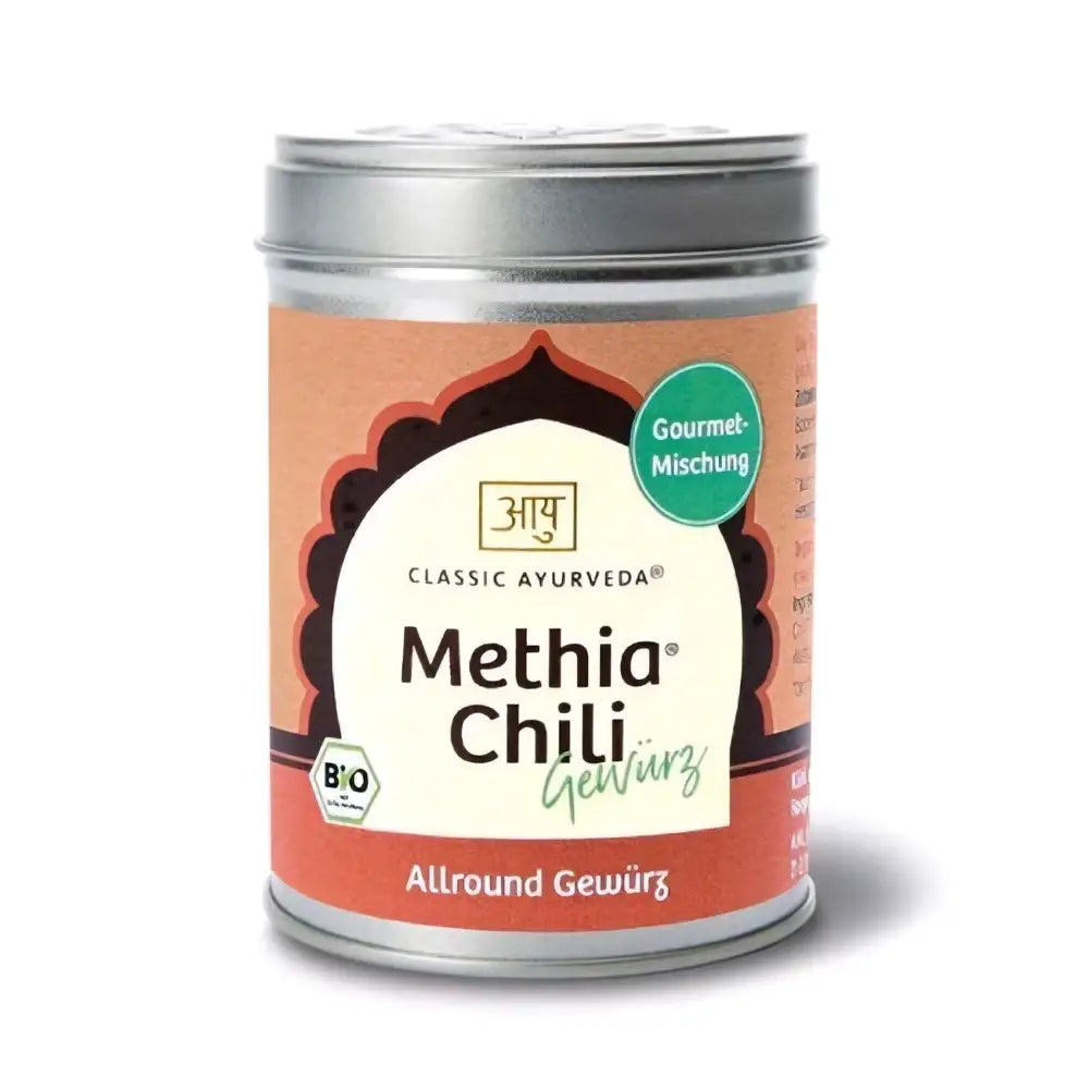 Ein zylindrisches bio-gewürzmischung tin mit silbernem deckel und orangenem label für classic ayurveda methia chili