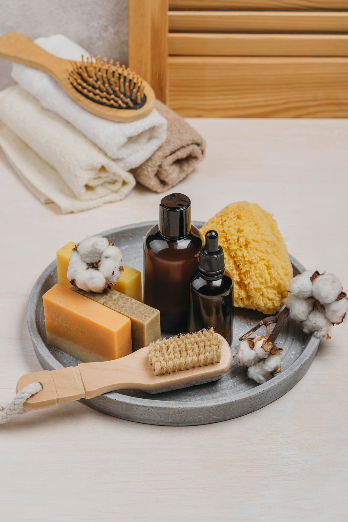 Naturkosmetik Set mit Bio-Seife, Öl in Braunglasflaschen, Schwamm und Haarbürste auf Tablett.