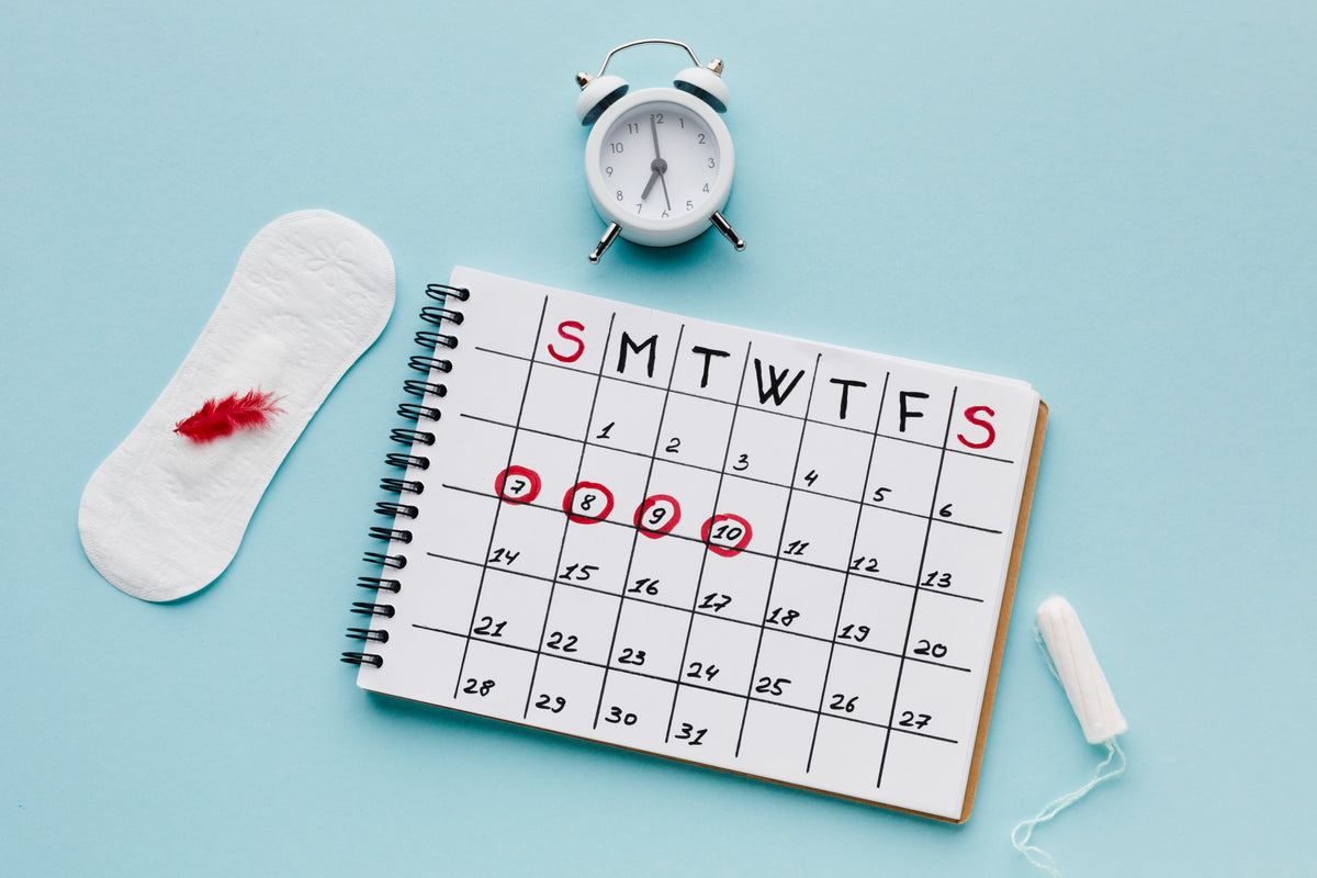 Kalender mit markierten Tagen, Damenbinde und Tampon auf blauem Hintergrund.