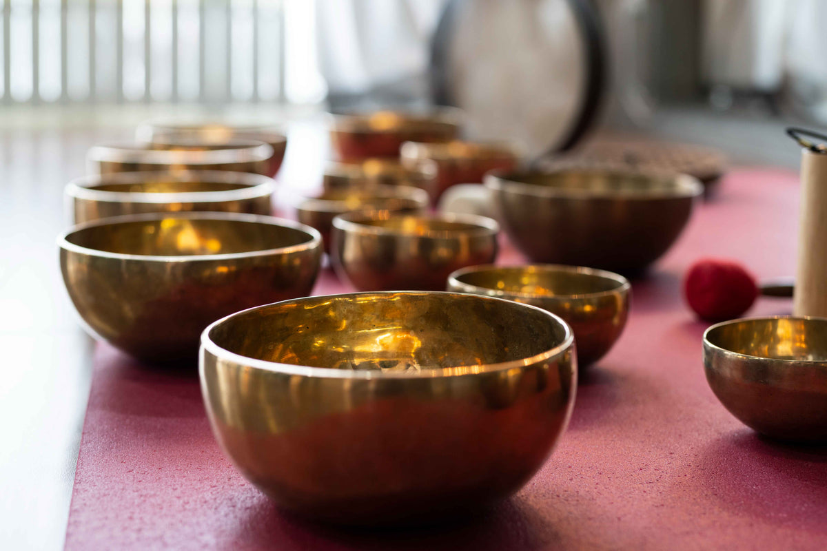 Goldene Klangschalen für Yoga und Meditation auf einer rosa Matte