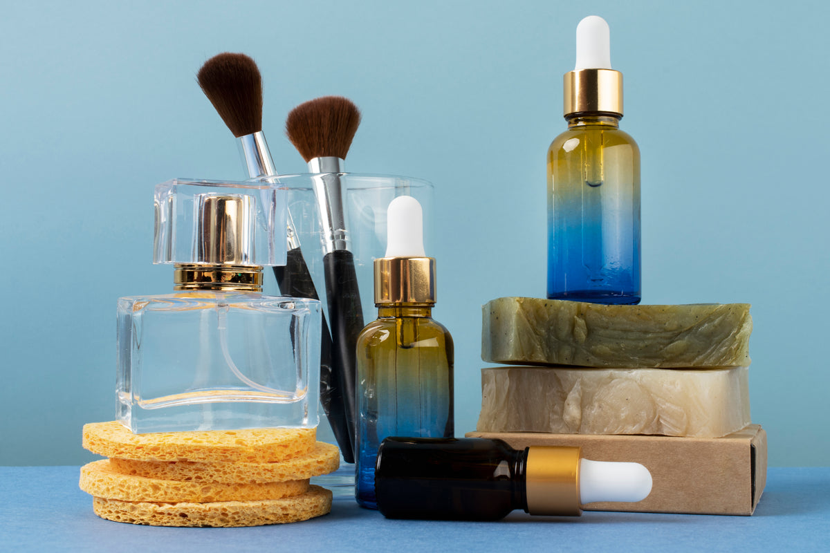 Bio-Kosmetik Set mit Serum, Parfüm, Naturseife und Make-up Pinseln auf blauem Hintergrund.