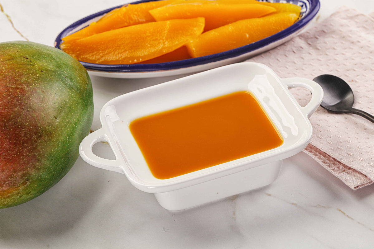 Frische Mango mit aufgeschnittenen Fruchtstücken und Mango-Püree in einer weißen Schale.