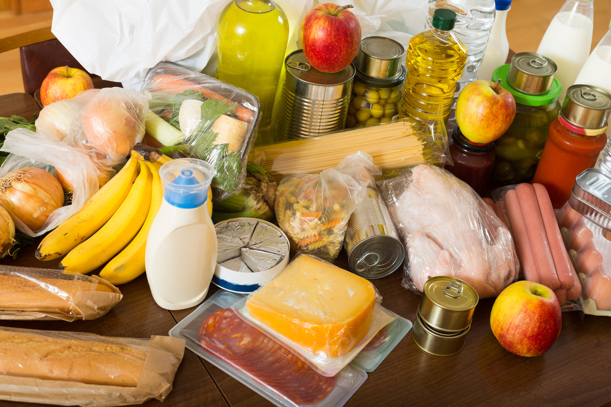 Vielfältige Lebensmittel wie Obst, Gemüse, Milchprodukte, Brot und Konserven auf einem Tisch.