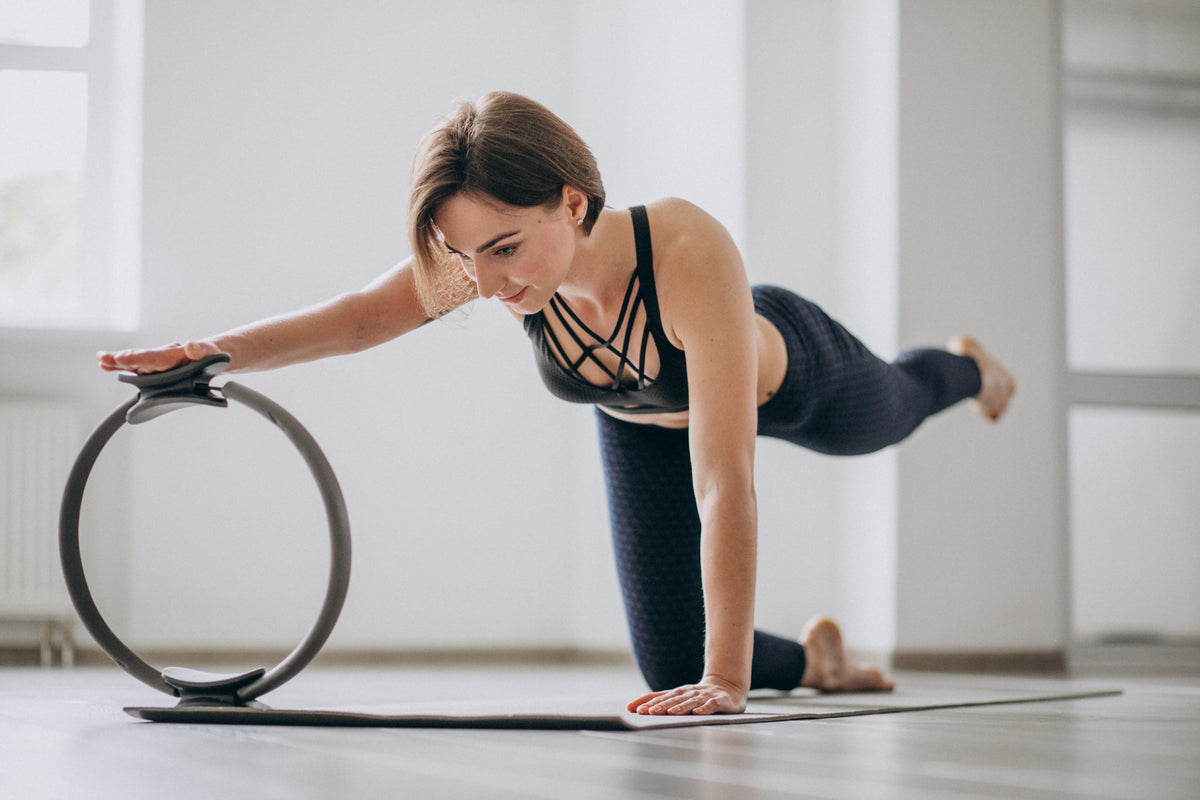 Frau macht Pilates-Übungen mit dem Pilates-Ring auf einer Matte.