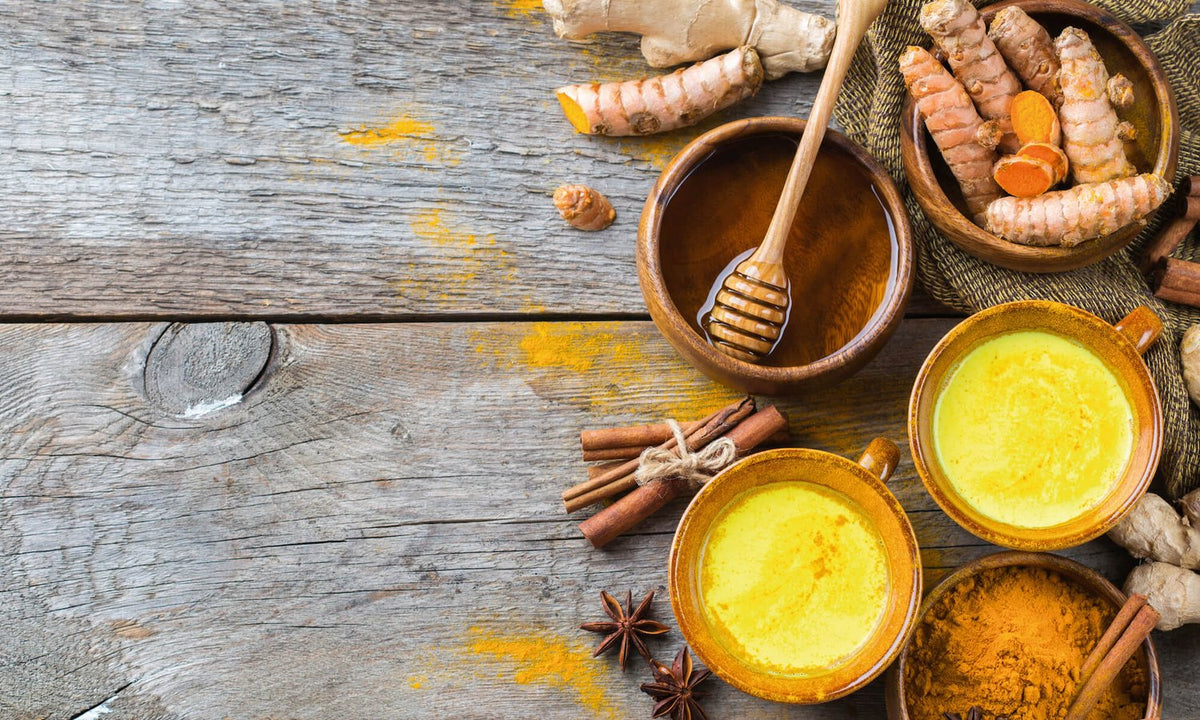 Goldener kurkumapulver in erdfarbenen keramikschalen mit frischem ingwer und zimtstangen bei ayurveda bern mana kendra