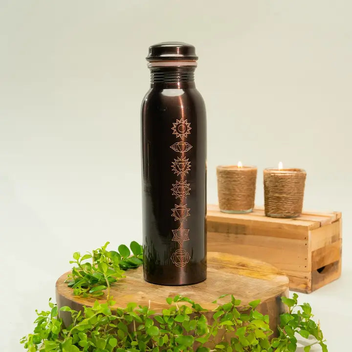 Ein dunkel kupferfarbener wasserflasche mit sieben goldenen chakra symbole für ayurvedische herbstmassage und vata-ungleichgewicht erkennen