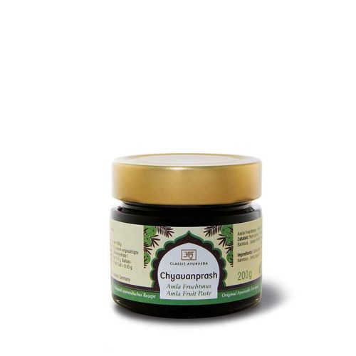 Ein dunkelgrünes glas mit golddeckel für chyavanprash amla fruchtpaste mit chyavanprash wirkung und charaka samhita text
