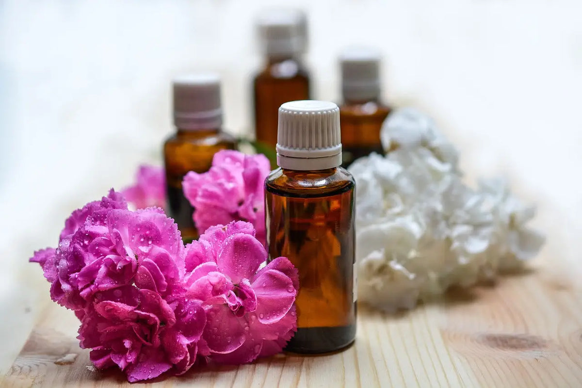 Amber glasflasche mit weißem geripptem verschluss umgeben von pinken und weißen blumen hochwertige bachblüten kaufen