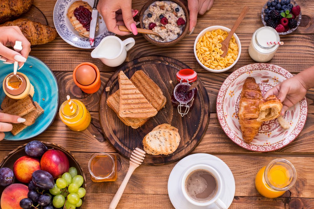 Rustikaler holztisch mit frühstück serviert mus fürs frühstück croissants toast haferbrei und frisches obst mana kendra