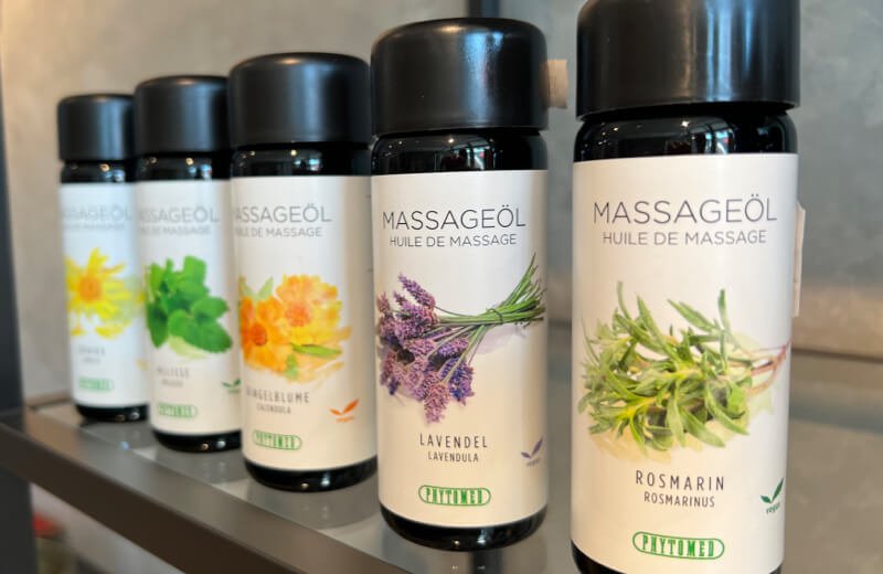 Schwarze glasflaschen mit schwarzen deckeln und weißen etiketts mit botanischen illustrationen massageöl im mana shop collection massage- und therapieprodukte