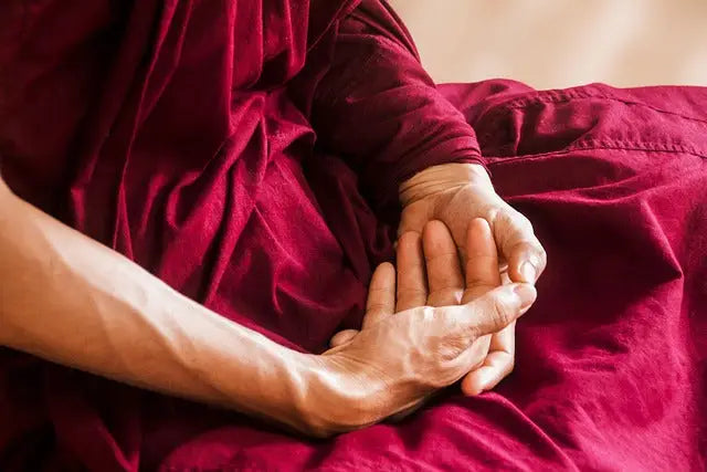 Ein paar hände in meditation auf hochwertigem roten samt für innere balance im mana shop collection