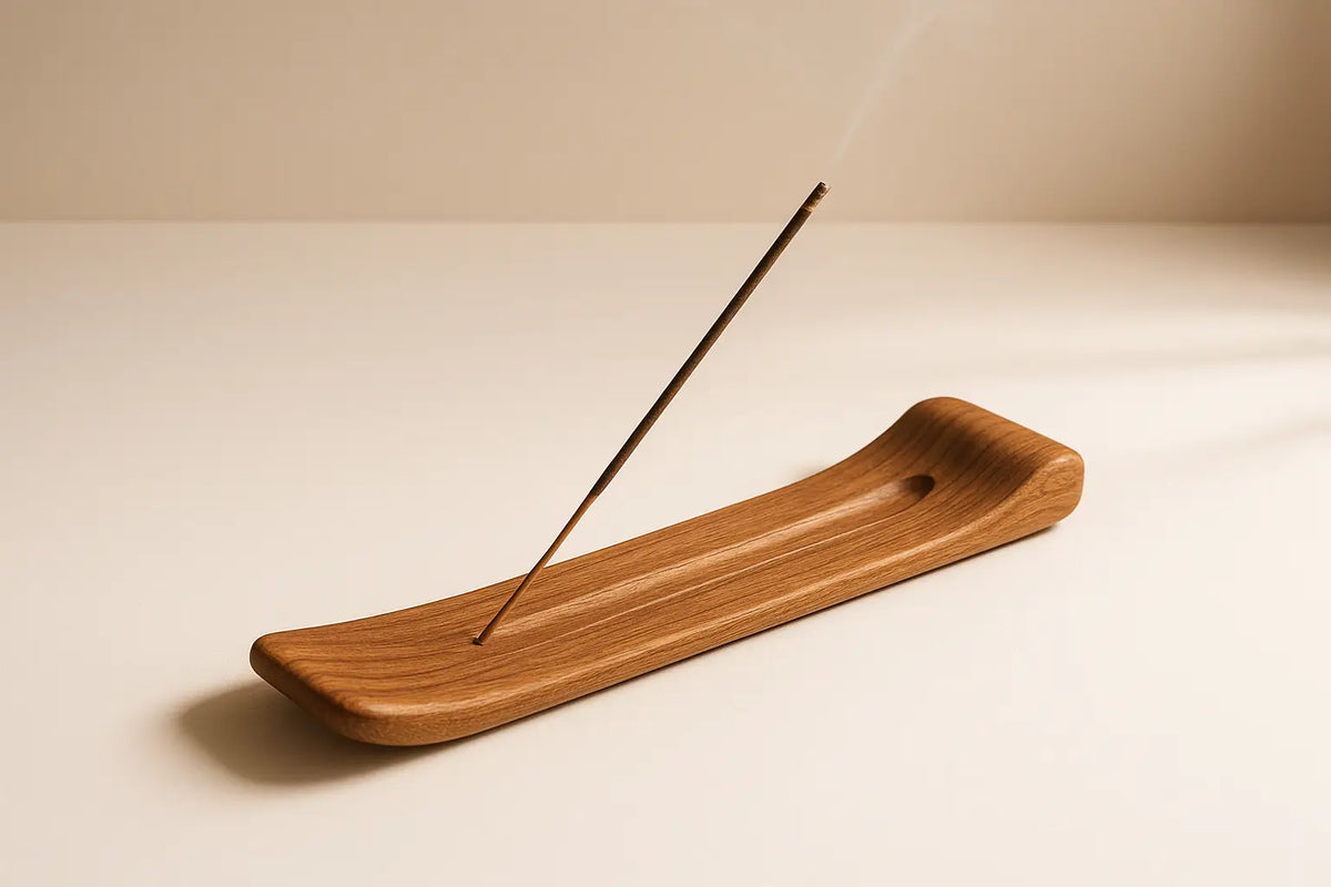 Ein lichtbrauner, geschwungener räucherstäbchenhalter aus holz mit einem einzelnen räucherstäbchen für besondere atmosphäre im mana shop