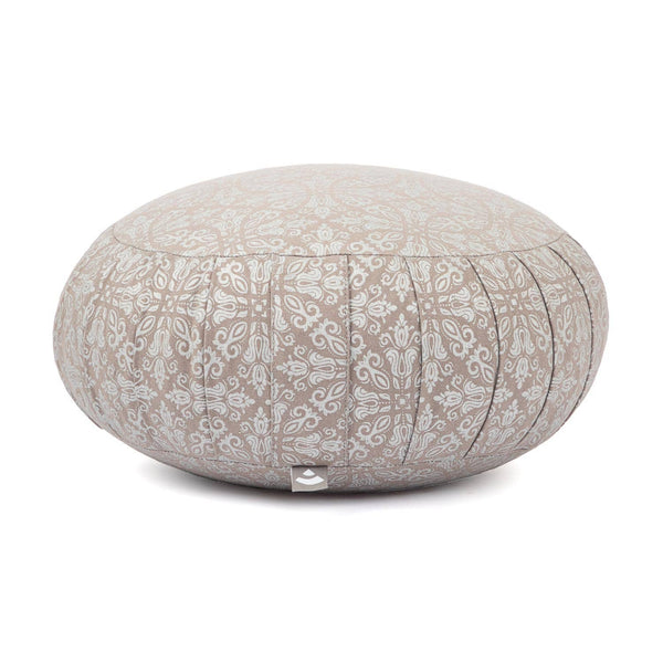 Ein runder Meditationskissen in hellem Beige mit einem weißen dekorativen Muster, von der Seite gezeigt. Das Kissen hat ein kleines Etikett an der Unterseite, und sein Design wird vor einem weißen Hintergrund hervorgehoben