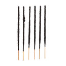 Sechs dunkle, dick beschichtete Räucherstäbchen auf weißem Hintergrund.