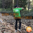 Ein Mann in einem grünen Hemd geht über einen mit Tannenzapfen bedeckten Waldweg am Lake Tahoe.