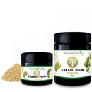 Zwei schwarze Gläser Ancient Purity Kakadu-Pflaumenpulver neben einem Haufen hellbraunem Pulver.