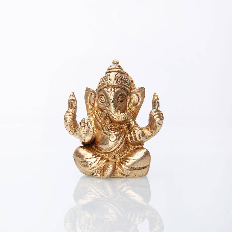 Goldene sitzende Ganesha-Statue mit detaillierten Verzierungen, Elefantenkopf, erhobenen Händen zum Segen und dekorativer Krone, auf weißem reflektierendem Hintergrund.