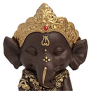 Nahaufnahme des Gesichts einer meditierenden dunkelbraunen Ganesha-Statue mit goldener Krone.