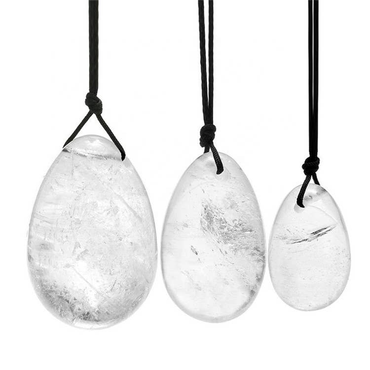 Set aus drei polierten, glatten, eiförmigen Klarquarz-Anhängern in verschiedenen Größen (groß, mittel, klein), die jeweils an einer geknoteten schwarzen Kordel hängen.