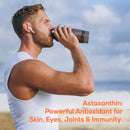 Ein Mann in einem weißen ärmellosen Shirt trinkt aus einer Flasche. Auf dem Bild steht der orangefarbene Text: „Astaxanthin: Powerful Antioxidant for Skin, Eyes, Joints & Immunity.“
