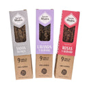 Eine Produktaufnahme von drei vertikalen Sagrada Madre Räucherstäbchenverpackungen der Línea Hierbas-Serie. Jede Packung enthält 9 dicke Stäbchen (varillas gruesas), ist als 100% Natur gekennzeichnet und in den Duftrichtungen Salvia Blanca (Weißer Salbei, graue Schachtel), Lavanda y Olíbano (Lavendel und Weihrauch, lila Schachtel) und Rosas y Olíbano (Rosen und Weihrauch, rote Schachtel) erhältlich.
