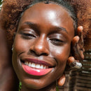 Nahaufnahme einer lächelnden Frau mit strahlender Haut und lockigem Haar.