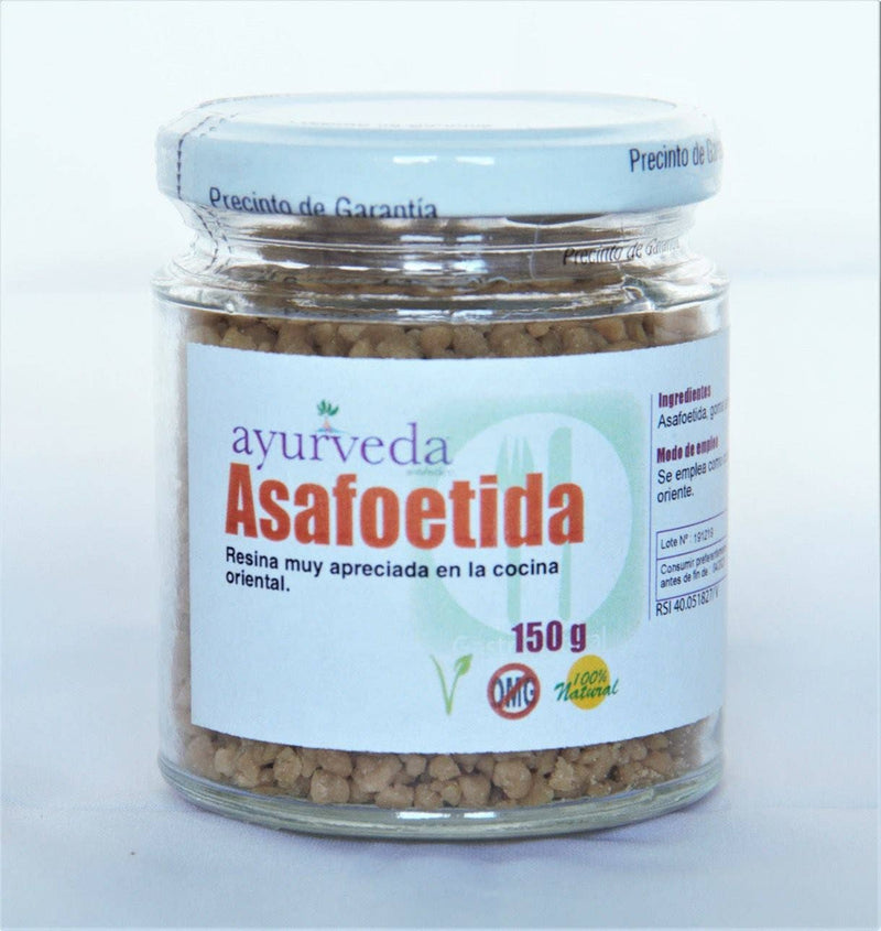 Ein klares Glas mit weißem Deckel, das 150g körniges braunes Asafoetida enthält. Das Etikett besagt, dass es ein in der orientalischen Küche geschätztes Harz und 100% natürlich ist.