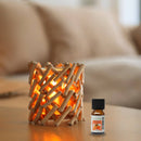 Eine Flasche des ätherischen Öls Zen'Arôme Orange steht neben einem rustikalen Kerzenhalter aus Holz mit warm leuchtendem Licht in einer gemütlichen Umgebung.