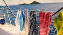 Mehrere bunte Handtücher, die an einer Wäscheleine auf einem Boot auf See hängen.