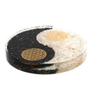 Eine Yin-Yang-Scheibe aus schwarzen und weißen Steinen mit goldenen, geometrischen Mustern.