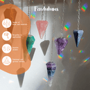 Verschiedene facettierte Pendel aus farbigen Steinen hängen vor einem sonnigen Fenster und erzeugen regenbogenfarbene Lichtreflexionen. Die Grafik hebt die Vorteile von Pendeln hervor, wie ihre Vielseitigkeit, intuitive Antworten und emotionales Wohlbefinden.