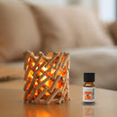 Eine Flasche des ätherischen Öls Zen'Arôme Orange steht neben einer rustikalen Holzlaterne mit warmem Licht auf einem Tisch in einem gemütlichen Wohnzimmer.