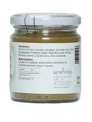 Masala Churna in einem Glas mit weißem Deckel. Das weiße Etikett listet Gewürzzutaten wie Koriander und Kreuzkümmel auf und enthält Kontaktdaten für Ayurveda.