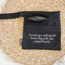 Eine schwarze wasserdichte Reise-Tasche mit zwei Fächern und Druckknopfband, von Bamboozy, auf einer gewebten Matte präsentiert.
