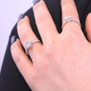 Die Hand einer Frau, die zwei silberne Diamantringe mit funkelnden Pavé-Ringschienen trägt.