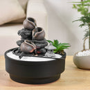 Ein Desktop-Zen-Garten mit einem dreistufigen Wasserbrunnen, weißem Sand und einer kleinen Steinlaterne.