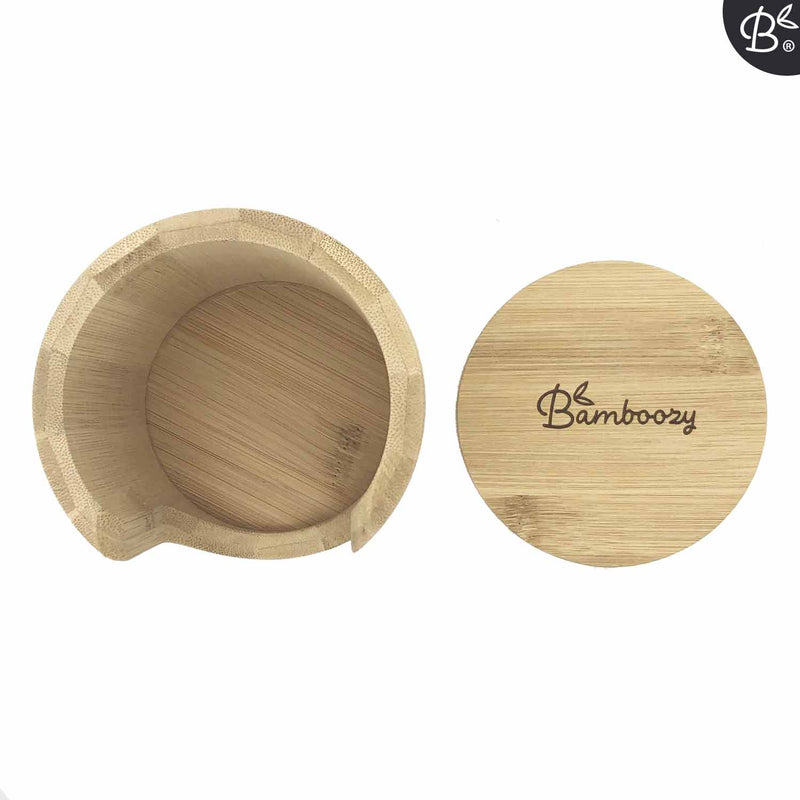 Draufsicht auf einen runden Bambushalter mit "Bamboozy"-Logo auf dem Deckel, positioniert neben dem leeren zylindrischen Unterteil mit einer Aussparung für einfachen Zugriff.