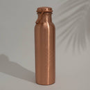 Eine Kupfer-Wasserflasche mit einem eingravierten Blume des Lebens Symbol, auf einem einfarbigen Hintergrund mit Schatten.